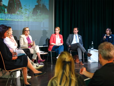 Menschen sitzen am Podium bei einer Diskussion