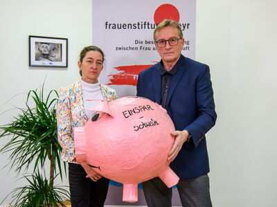 Klaudia Burtscher und Josef Pürmayr halten das Einsparschwein, eine übergroßes Sparschwein